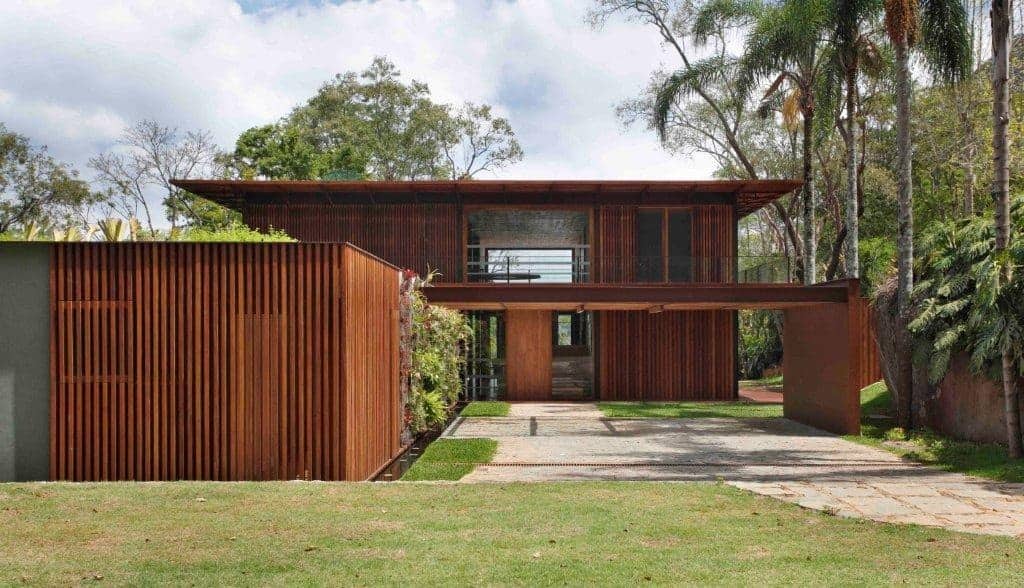 Modern wooden house with sleek architectural design and eco-friendly elements, surrounded by lush greenery and tall trees, exemplifies contemporary architecture and innovative home design.