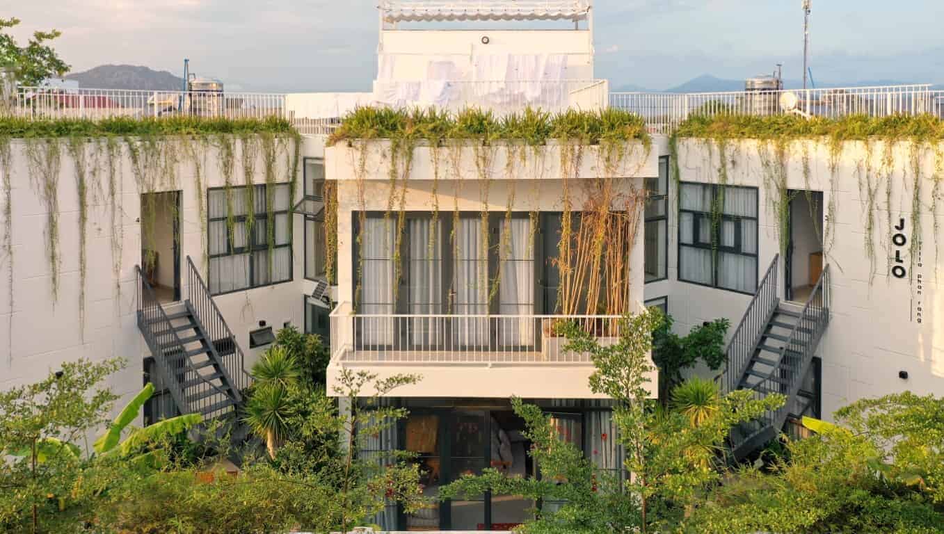 Modern urban rooftop garden with greenery and stylish architecture, featuring outdoor staircases and large glass windows in a contemporary building.