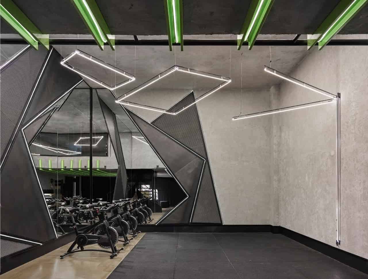 Futuristic gym interior with modern lighting, geometric wall design, and workout bikes, showcasing innovative architecture and contemporary fitness space design.