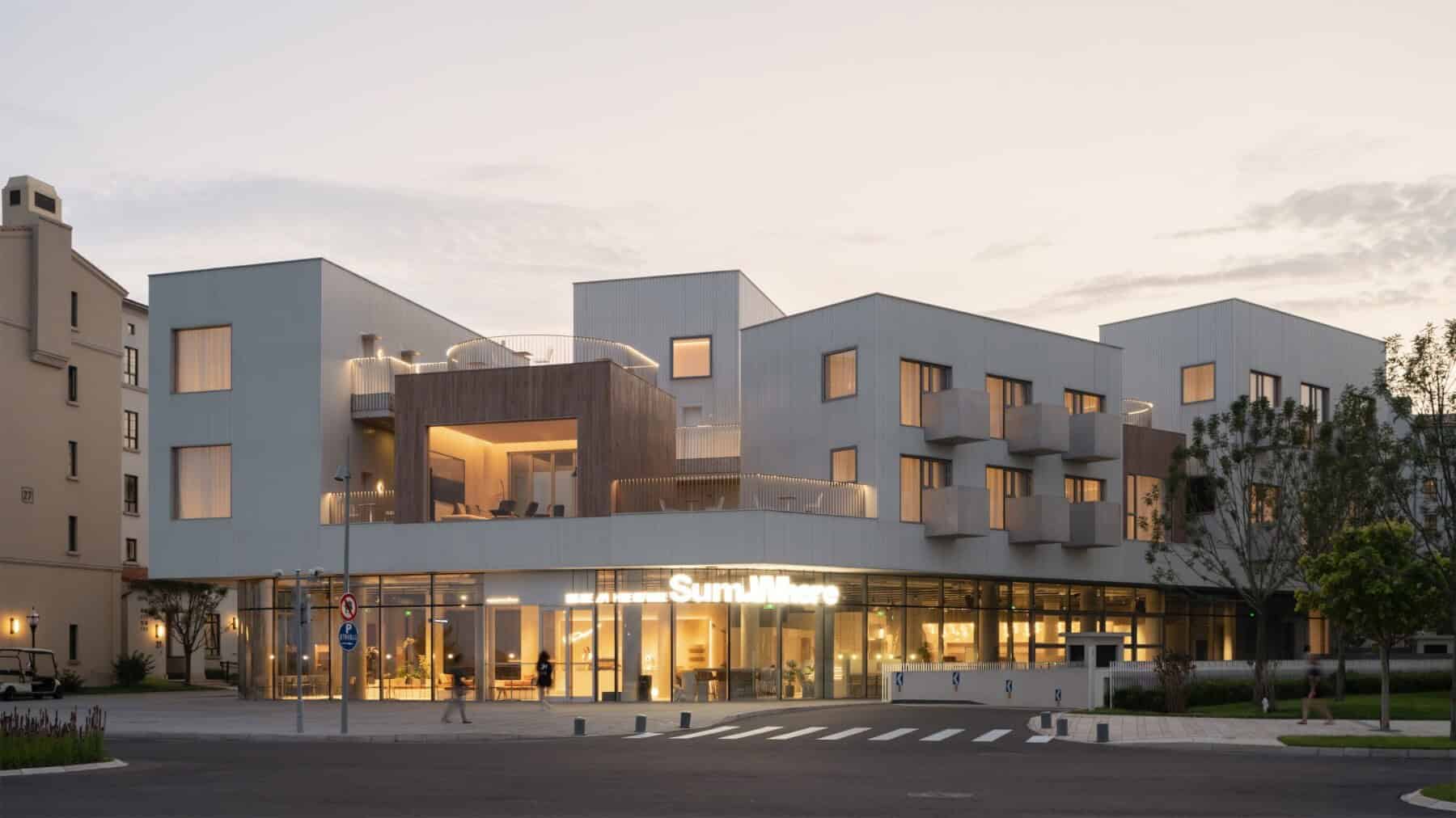 Modern mixed-use building with contemporary architecture, clean lines, and illuminated retail storefronts, highlighting innovative urban design, residential and commercial spaces, and eco-friendly building materials.