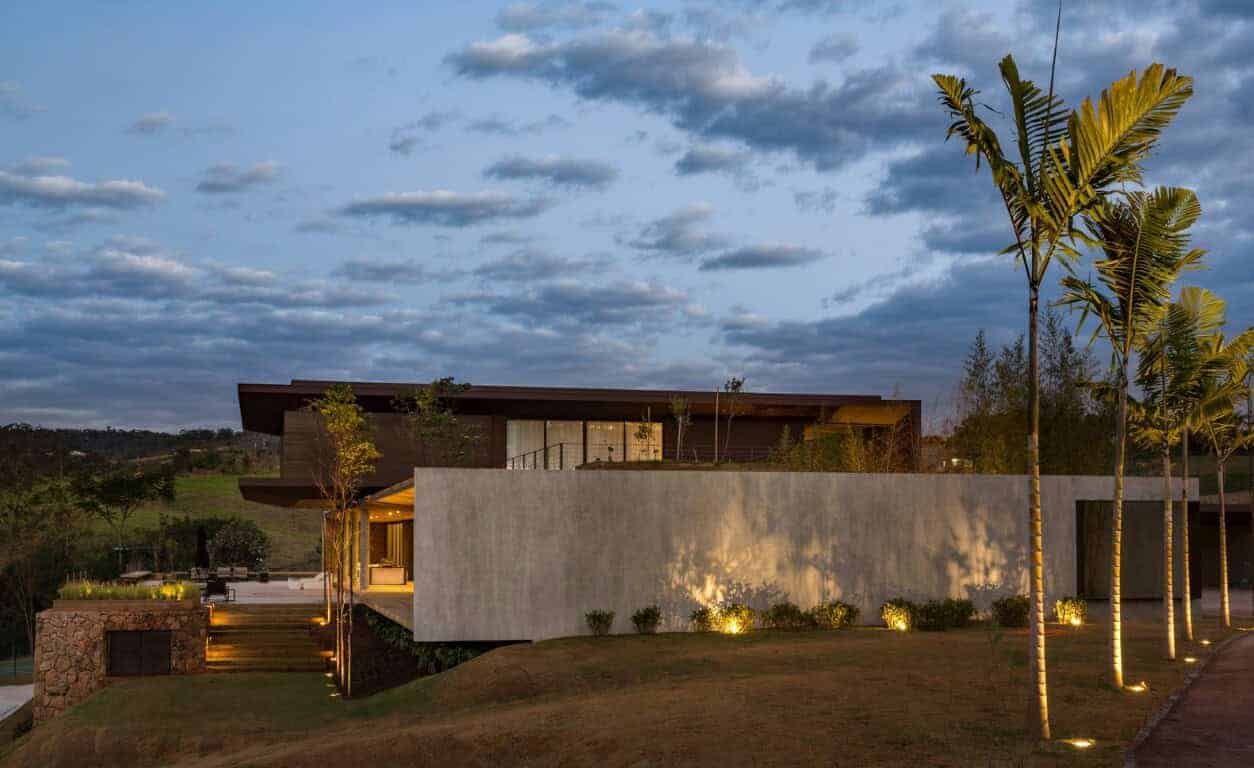 Luxury modern house with minimalist design and landscape lighting in a scenic countryside setting at dusk.