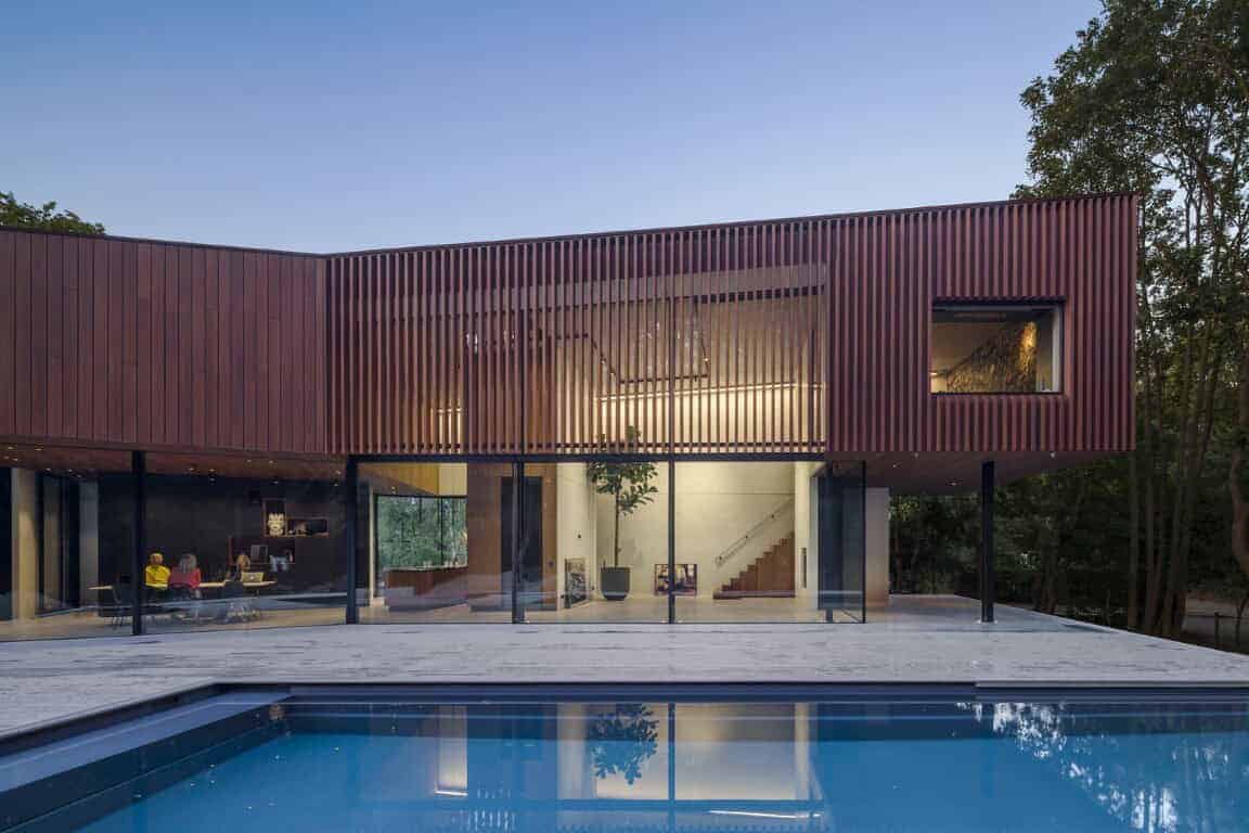 Contemporary modern house with sleek design, large glass windows, and a swimming pool, surrounded by lush greenery, showcasing innovative architecture and stylish outdoor living spaces.