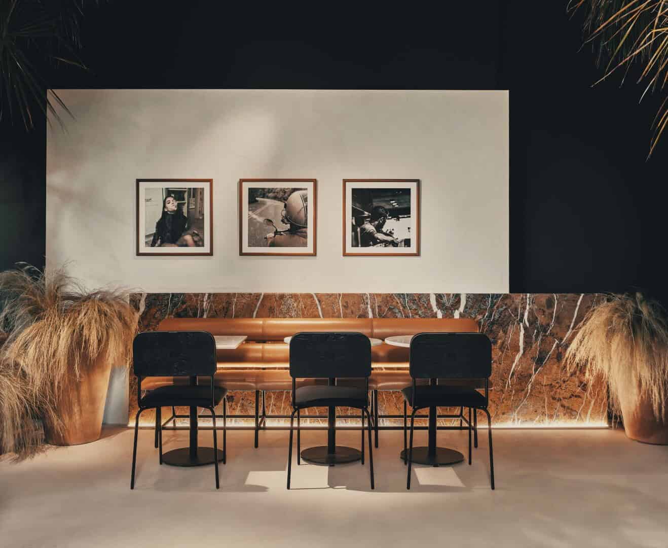 Modern interior design with black chairs and earthy accents, featuring contemporary artwork and textured marble wall, perfect for stylish cafes or lounge areas.