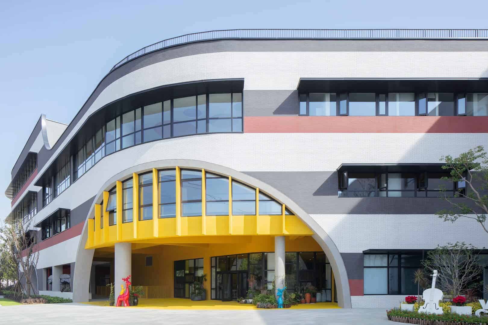 Colorful modern building with curved architectural design, large glass windows, and vibrant yellow accents, exemplifying innovative architecture and contemporary design elements.