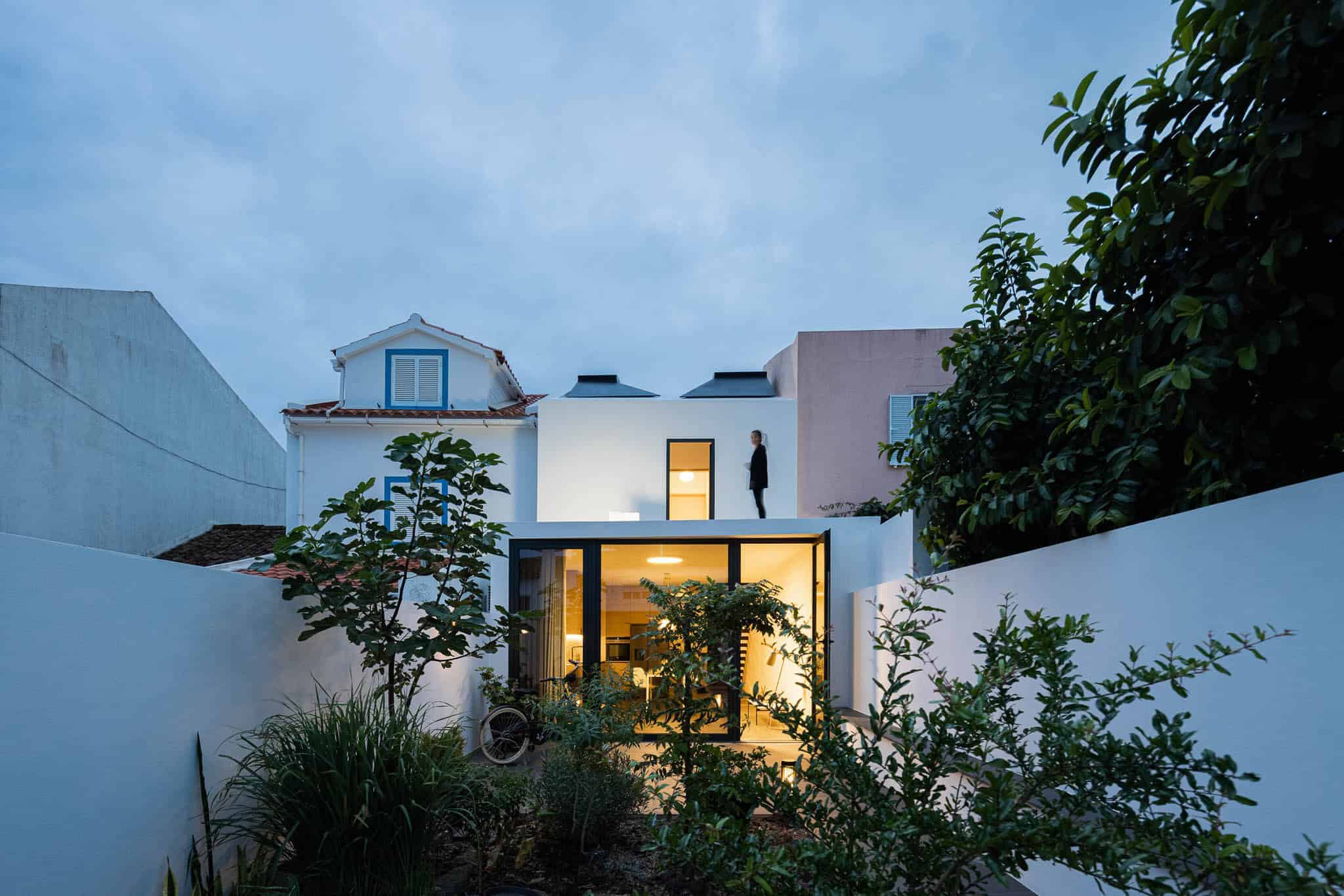 Contemporary modern house with glass extensions, lush garden, and urban surroundings, showcasing innovative architecture and innovative design principles.