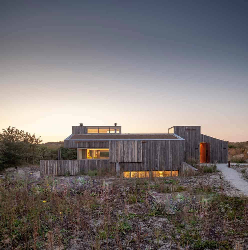 Modern wooden house with minimalist design, set in natural landscape during sunset, showcasing innovative architecture and eco-friendly materials for contemporary home design.