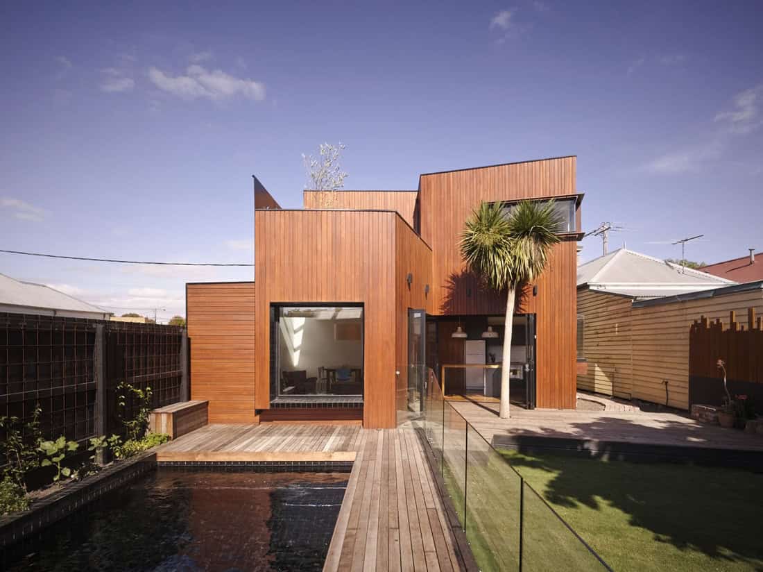 Modern wooden house with contemporary architectural design, featuring large glass windows, outdoor pool, and lush landscaping for stylish living.