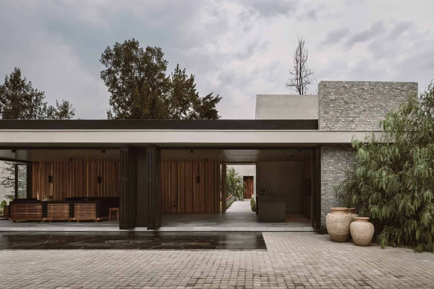 Modern suburban house with sleek architectural design, combining concrete and brick materials, surrounded by greenery and outdoor living spaces, ideal for contemporary architecture and home design.