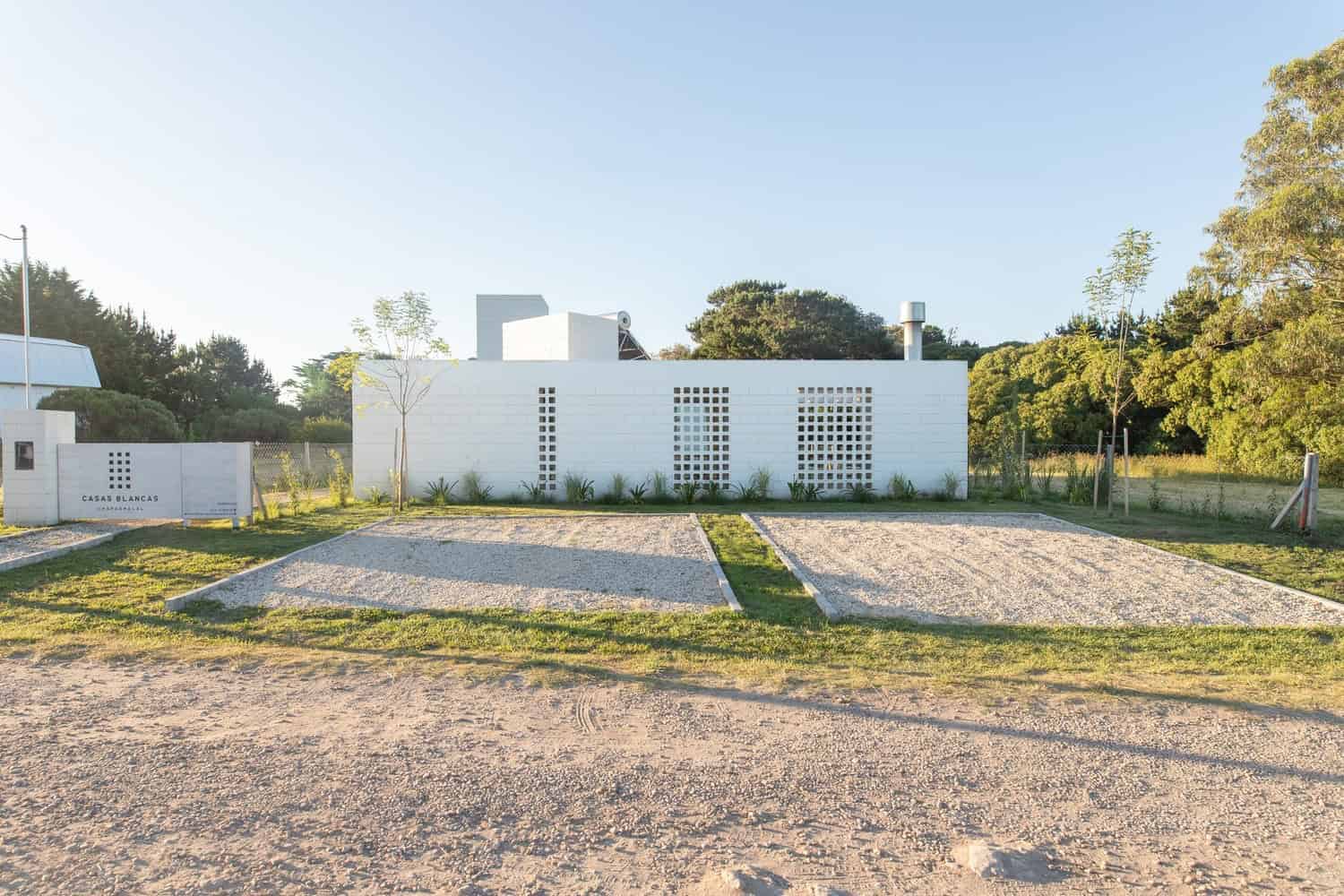 Modern minimalist white house with clean lines and contemporary design, surrounded by greenery and open space, showcasing innovative architecture and outdoor landscape planning.