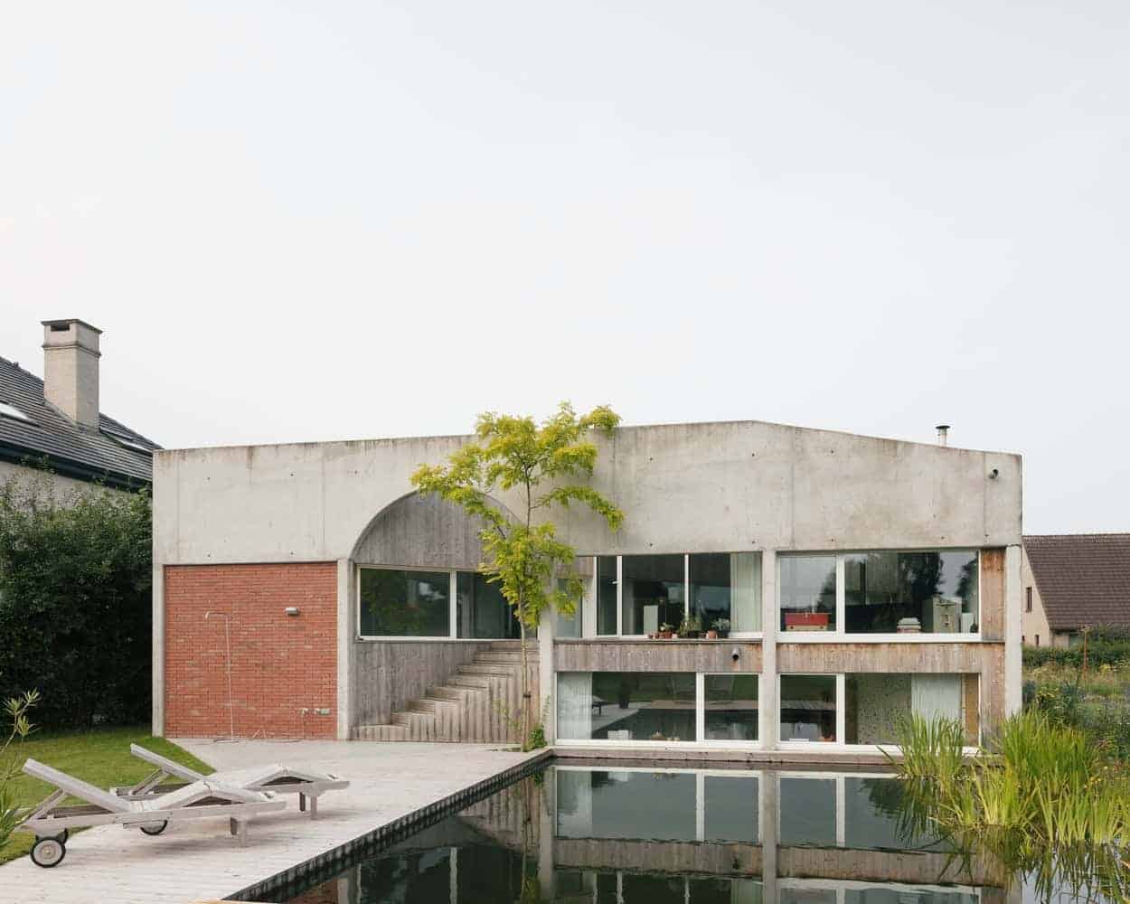 Modern concrete house with large glass windows and a pool, showcasing contemporary architecture and minimalist design.