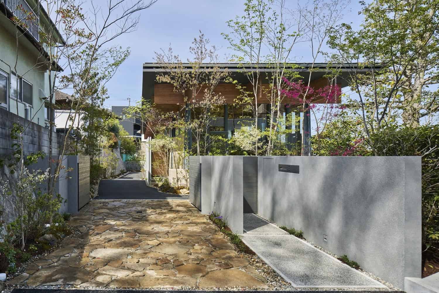 Contemporary modern house with a minimalist exterior, featuring sleek concrete walls, landscaped garden, and a stone pathway, showcasing innovative architecture and stylish outdoor design.