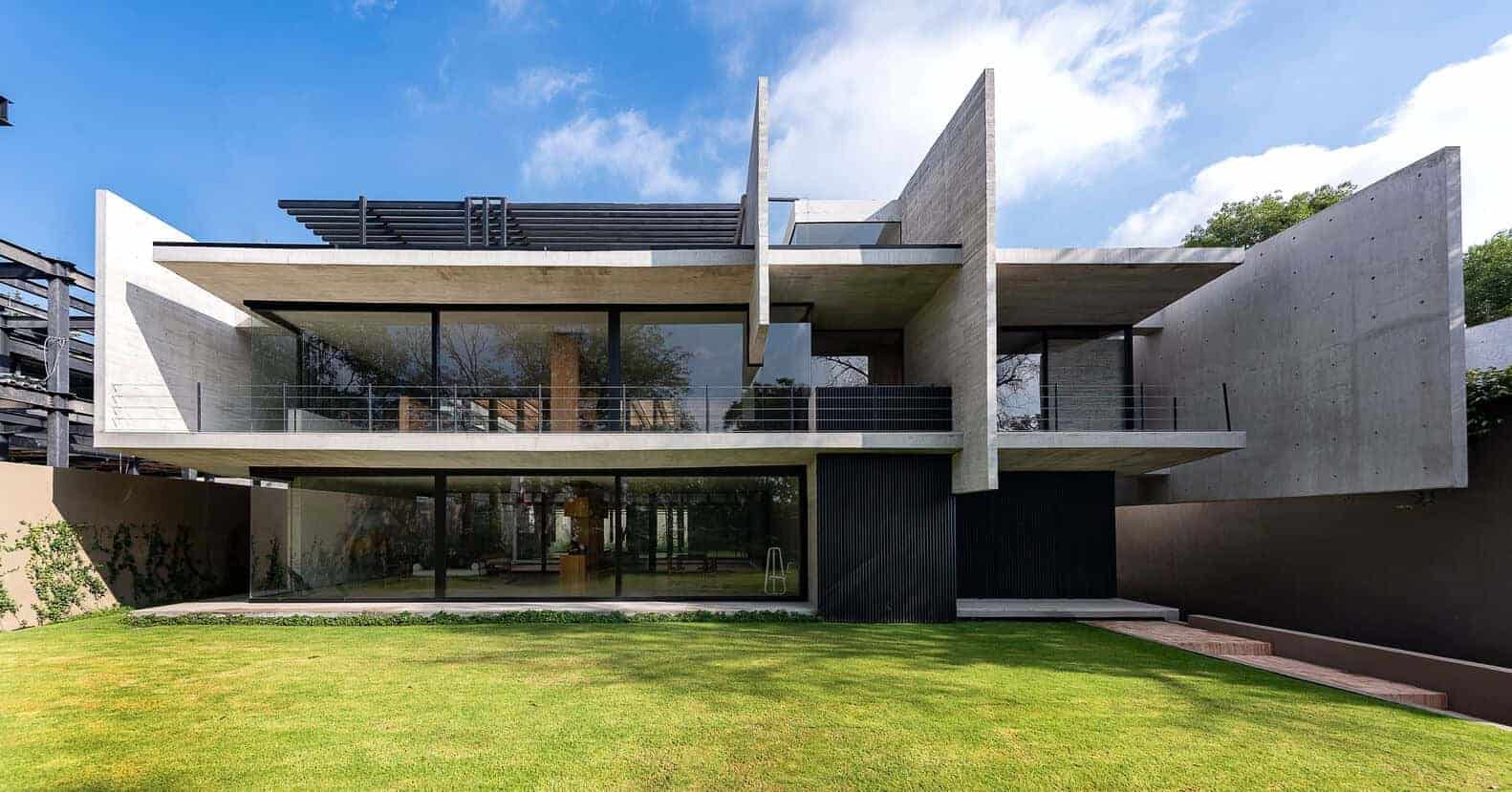 Contemporary modern house with minimalist architecture, concrete and glass facade, spacious balconies, and lush green lawn, showcasing innovative architectural designs.