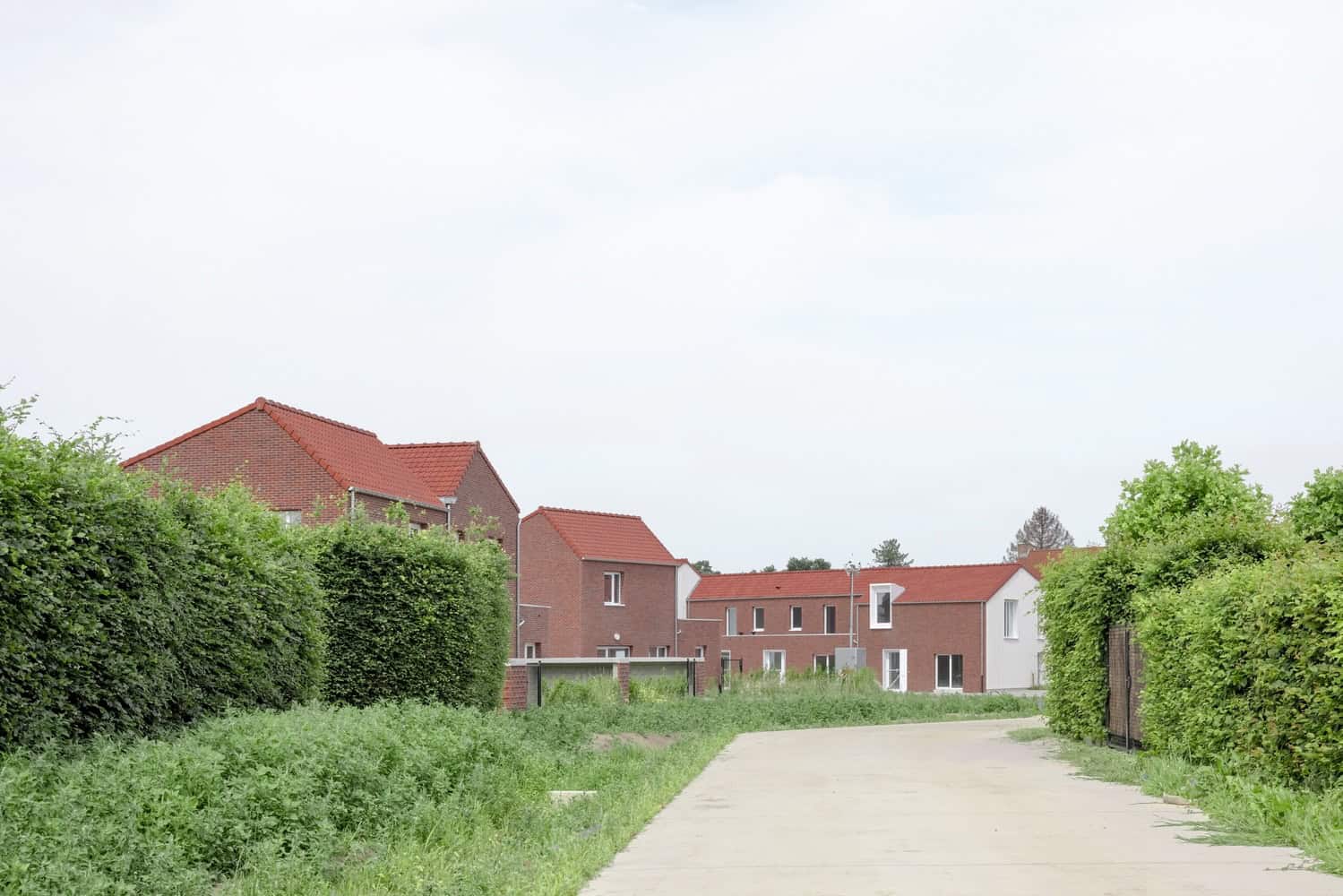 Contemporary residential houses with red tile roofs and lush green landscaping, showcasing modern architecture and design.