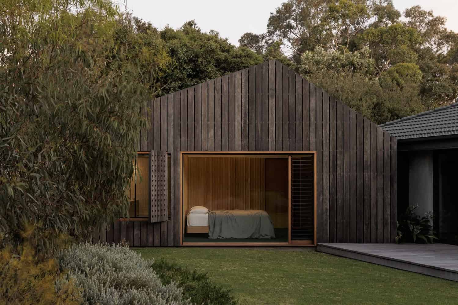 Modern wooden house with large glass sliding doors, minimalist design, surrounded by lush greenery, perfect for contemporary architecture and landscape integration.