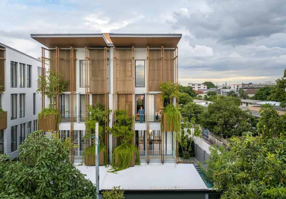 Modern eco-friendly architectural design with vertical wooden slats and lush greenery, emphasizing contemporary sustainable building concepts and innovative use of natural elements.
