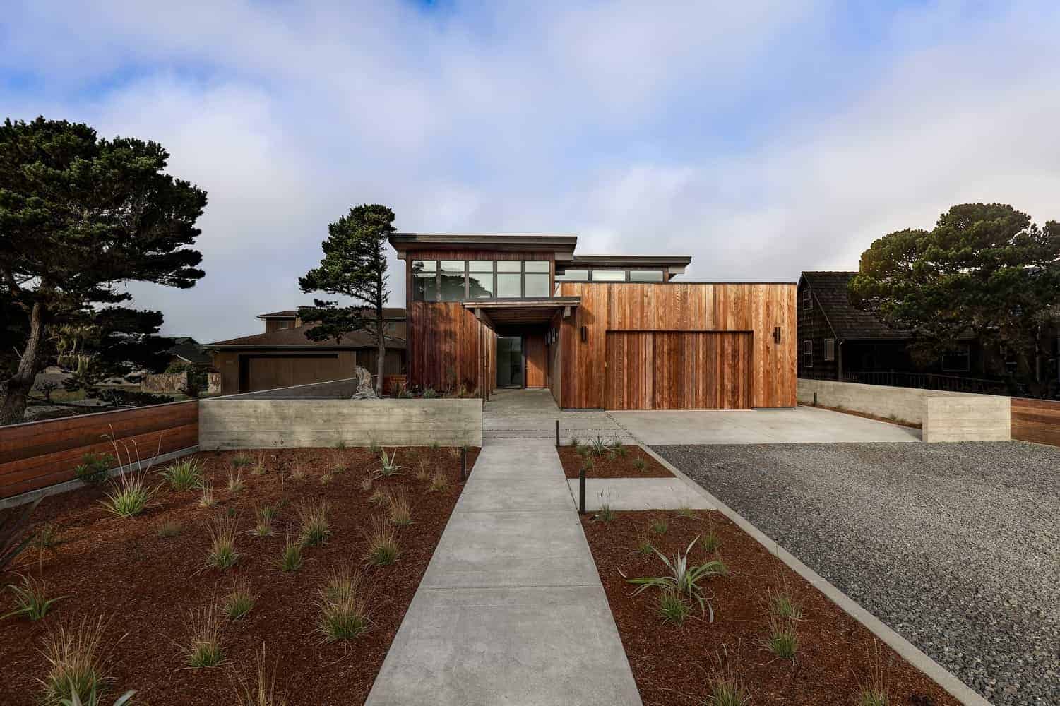 Modern minimalist house with wooden exterior and landscaped front yard, featuring contemporary architectural design and clean lines.