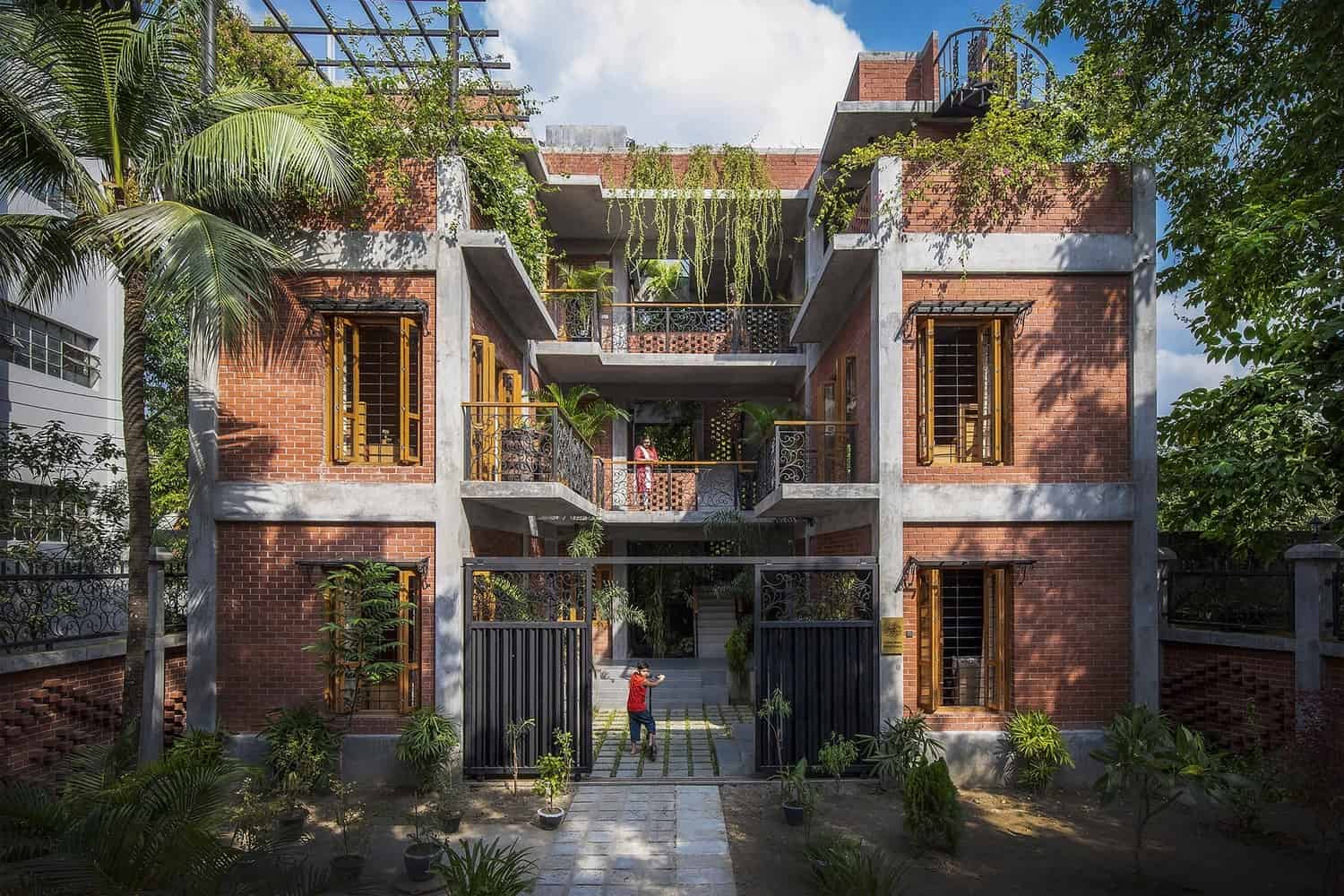 Elegant modern urban residential building with brick facade, lush rooftop garden, and contemporary balconies showcasing innovative architecture and green design elements.