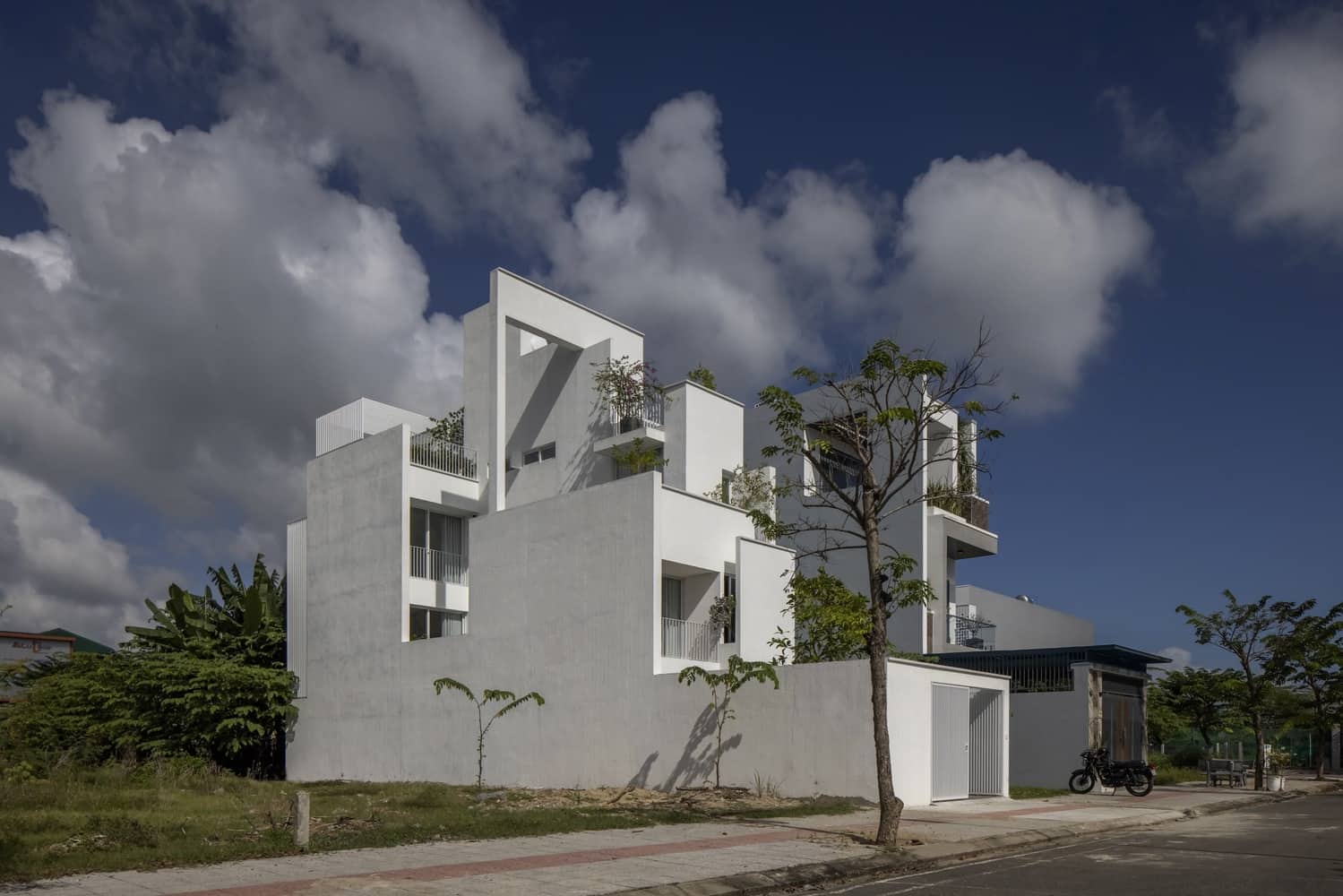 Modern white contemporary architectural building with geometric design, terraces, and greenery, showcasing innovative architecture and urban design.