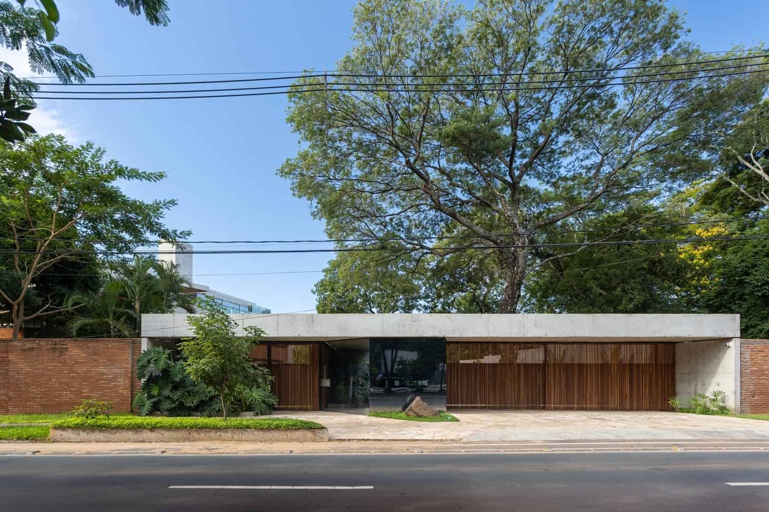 Sleek modern house with minimalist concrete facade, wooden accents, and lush greenery, exemplifying contemporary architecture and innovative design.