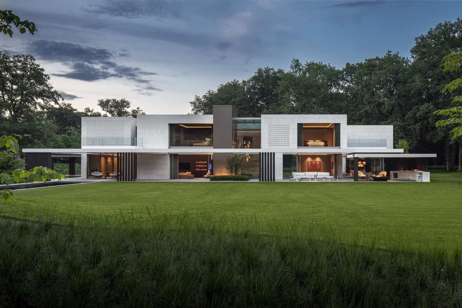 Sleek modern house with minimalist architecture featuring clean lines, large glass windows, and spacious outdoor living areas in a lush green landscape.