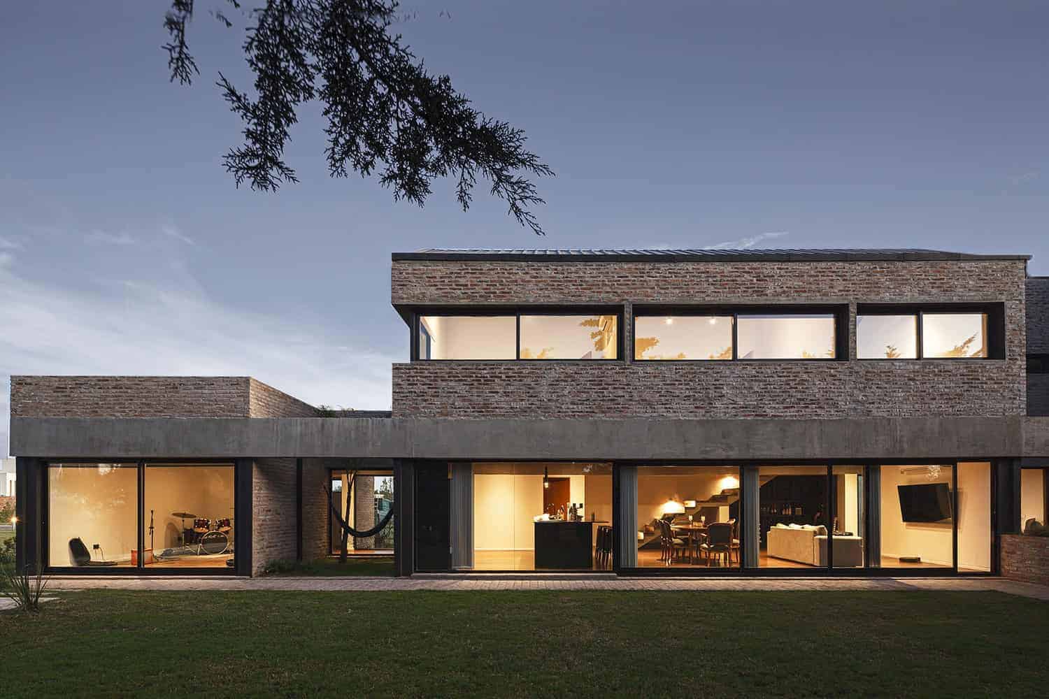 Modern brick and concrete residential house with large floor-to-ceiling windows showcasing contemporary architecture and stylish interior design.
