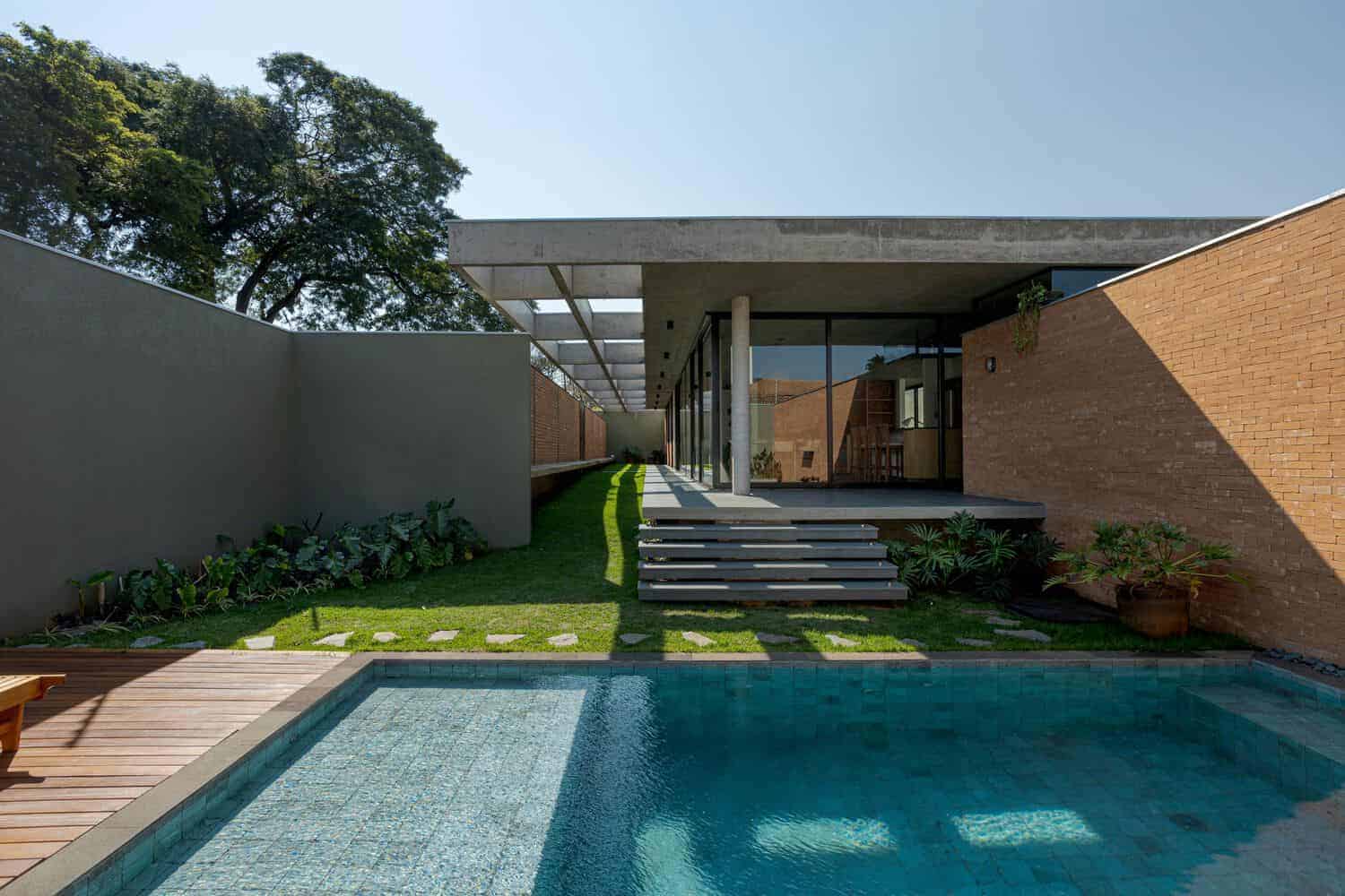 Contemporary modern house with minimalist architecture, pool, and outdoor garden area, featuring sleek concrete and brick design elements.