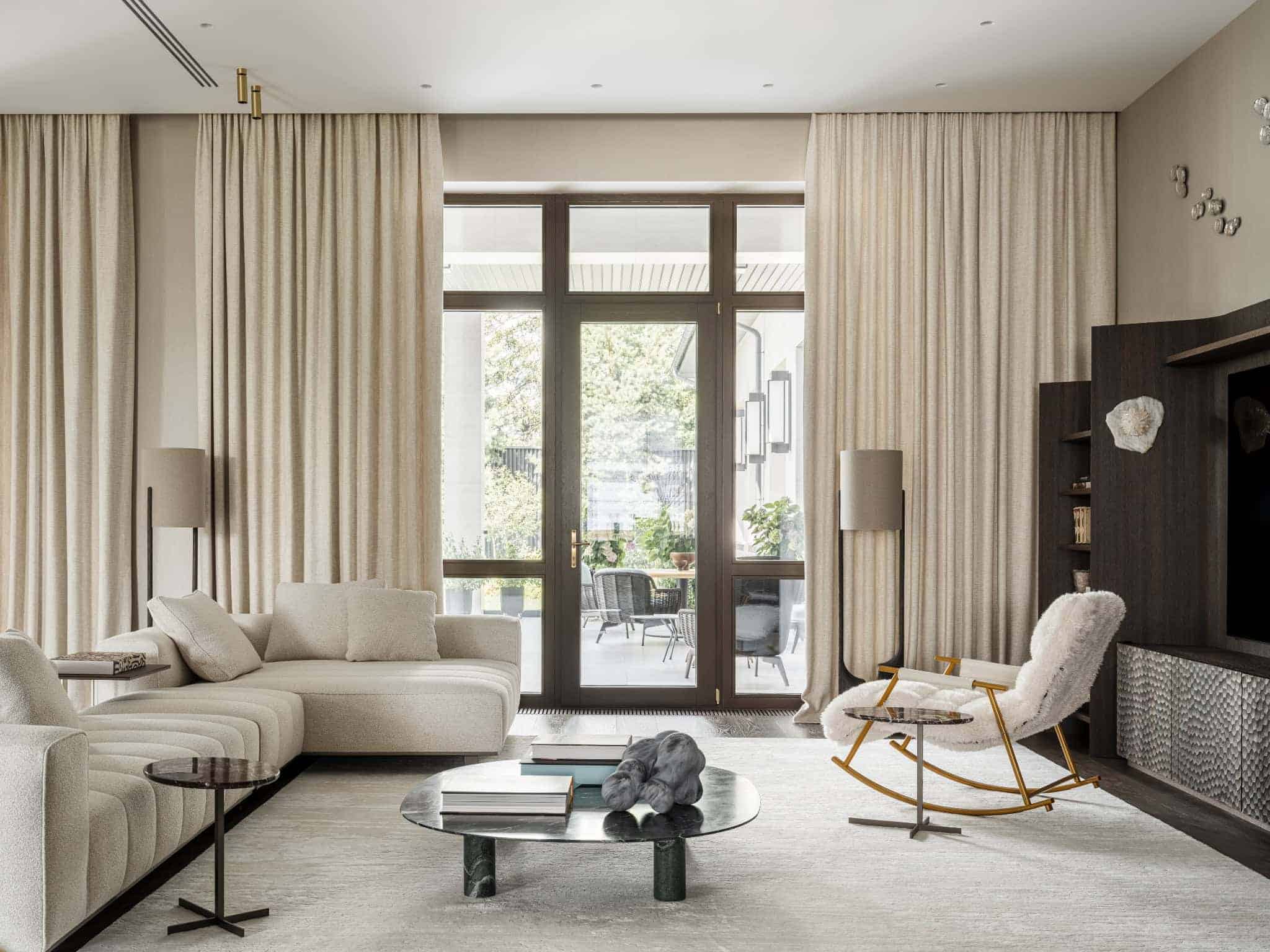 Luxurious modern living room interior featuring elegant beige curtains, a plush white sofa, and contemporary decor with natural light streaming through large glass doors.