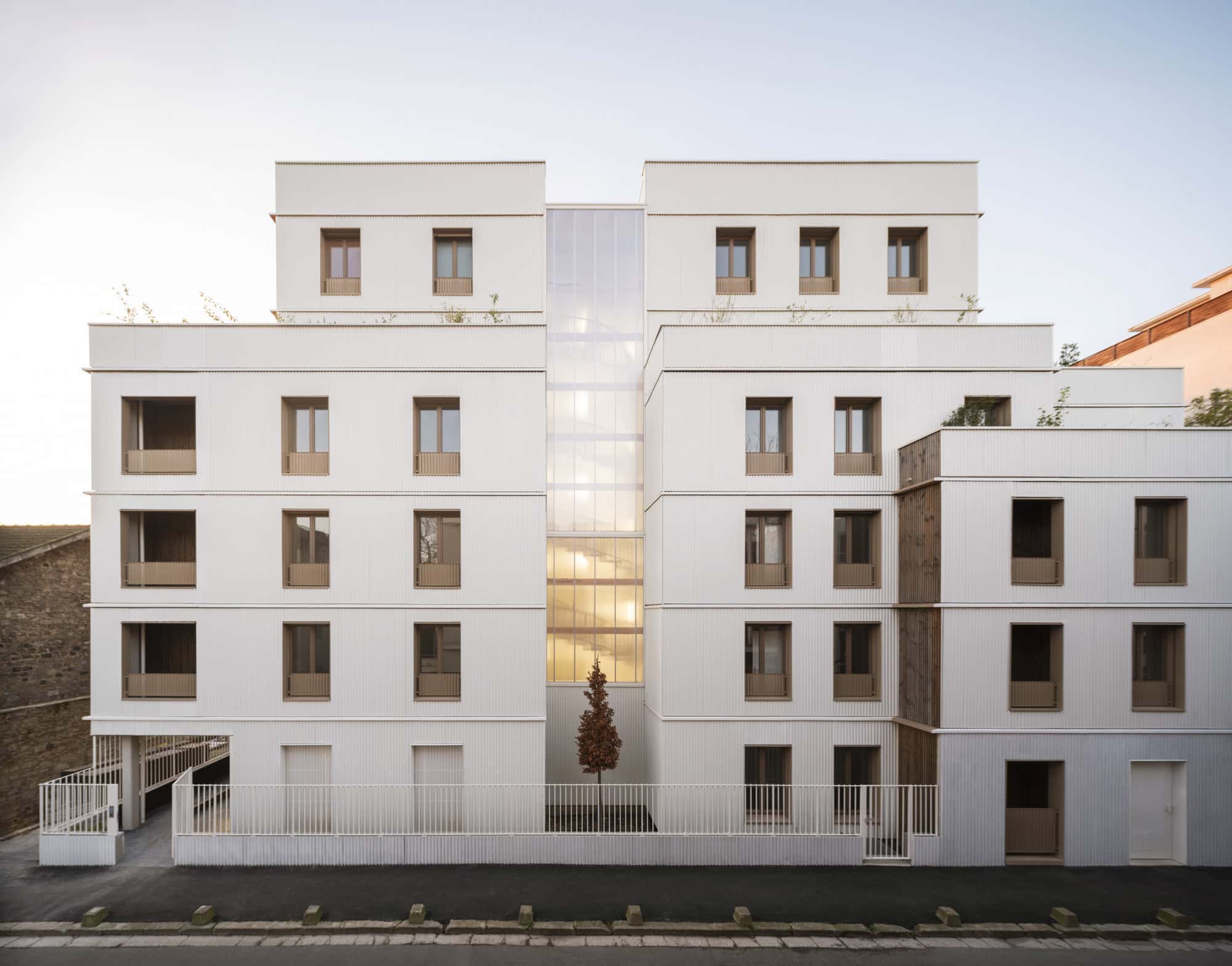 Contemporary white apartment building with minimalist design and large glass central feature, modern urban architecture, eco-friendly design, and sleek window aesthetics.