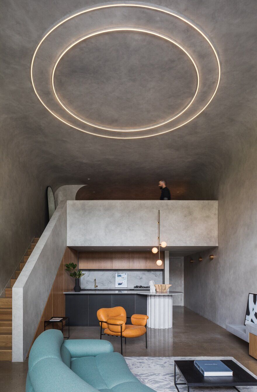 Modern minimalist interior with concrete ceiling featuring circular LED lighting, open-plan living space, colorful furniture, and contemporary kitchen design in neutral tones.