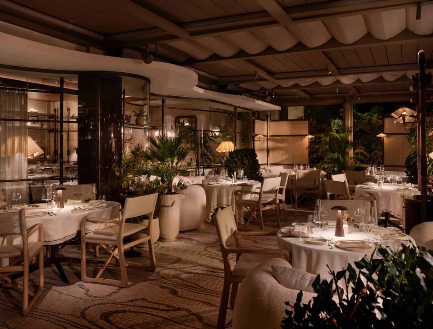 Elegant restaurant interior with modern design, warm ambient lighting, lush greenery, and stylish furniture creating a cozy atmosphere for fine dining.