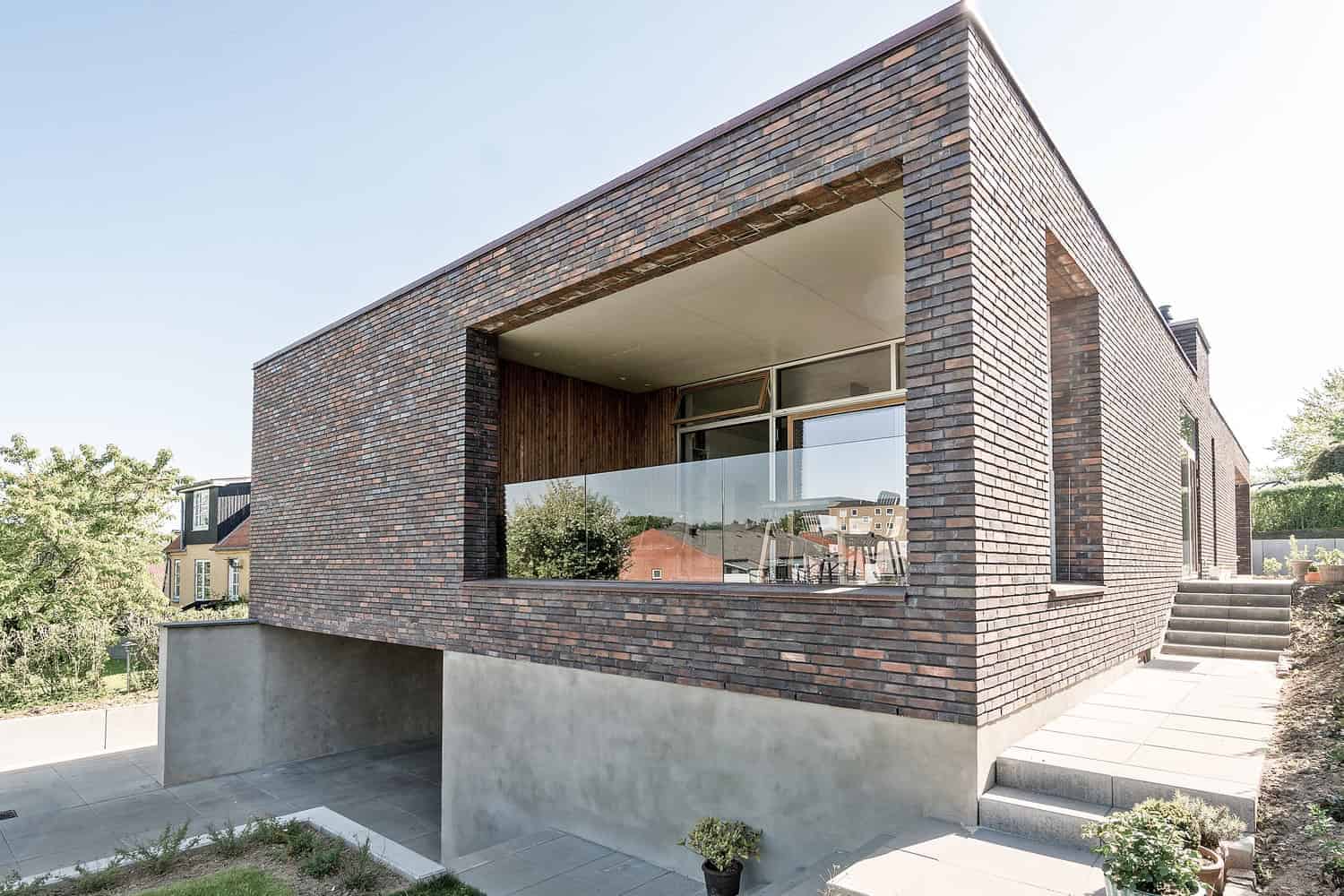 Contemporary brick house with modern architecture featuring a large balcony and glass railing.