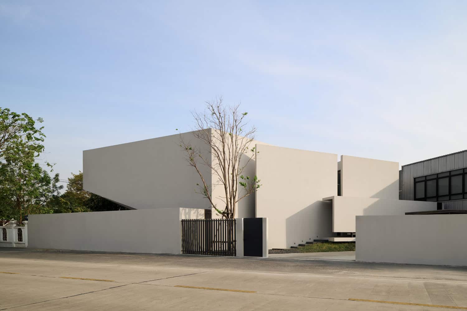 Contemporary white minimalist residential building with geometric design and clean lines, modern architecture, and outdoor landscaping.