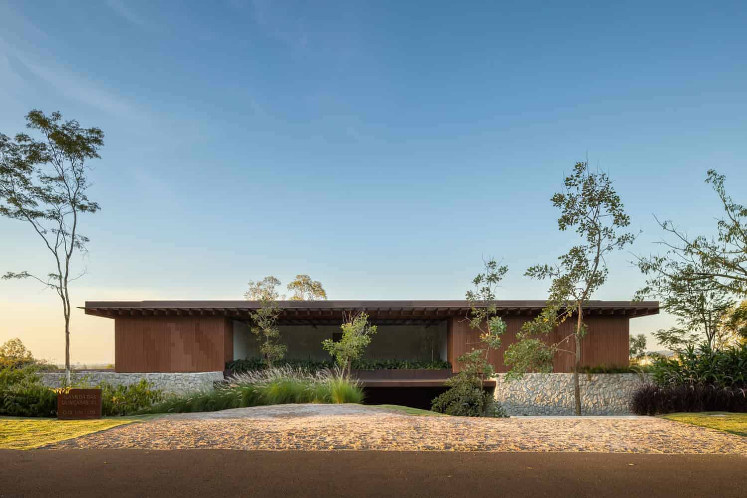 Sleek modern house with flat roof and natural stone accents, surrounded by landscaping, under a clear blue sky, exemplifying contemporary architecture design and eco-friendly building concepts.