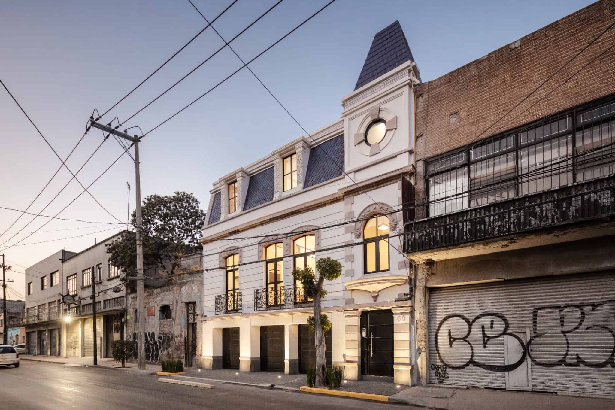 Elegant Victorian-style white building with classic architectural details, large windows, decorative iron balconies, and a distinctive rooftop tower, showcasing luxurious urban architecture.