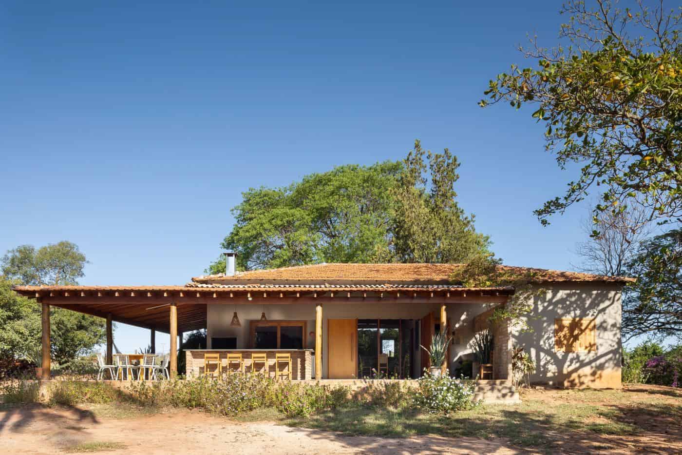 Modern rustic house with a spacious covered porch, natural wood accents, and a lush garden setting, showcasing innovative architecture and design ideas for eco-friendly homes.