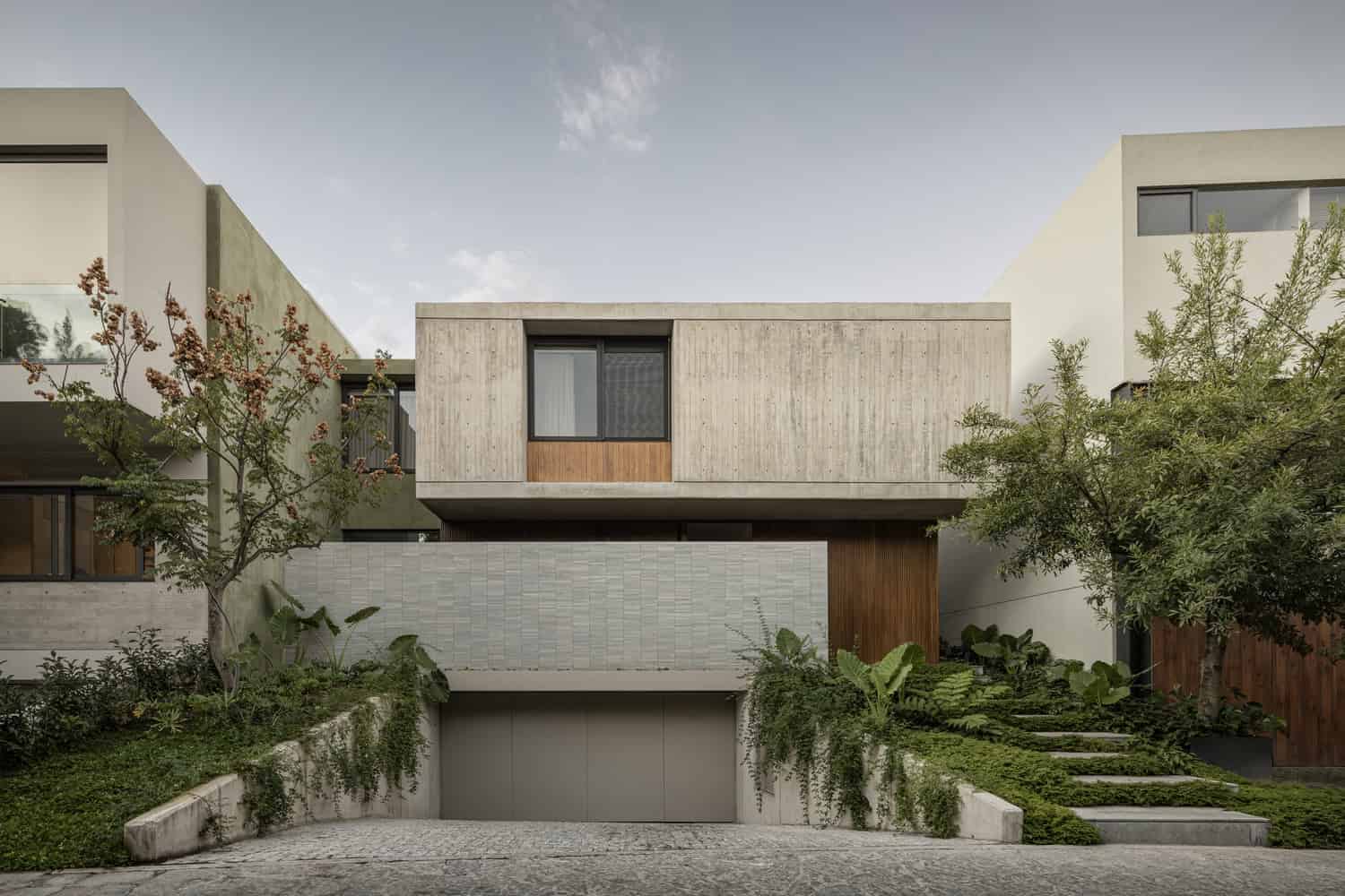 Contemporary modern residential house with minimalist architecture, concrete and wood facade, lush landscaping, and large windows, showcasing innovative architectural design.