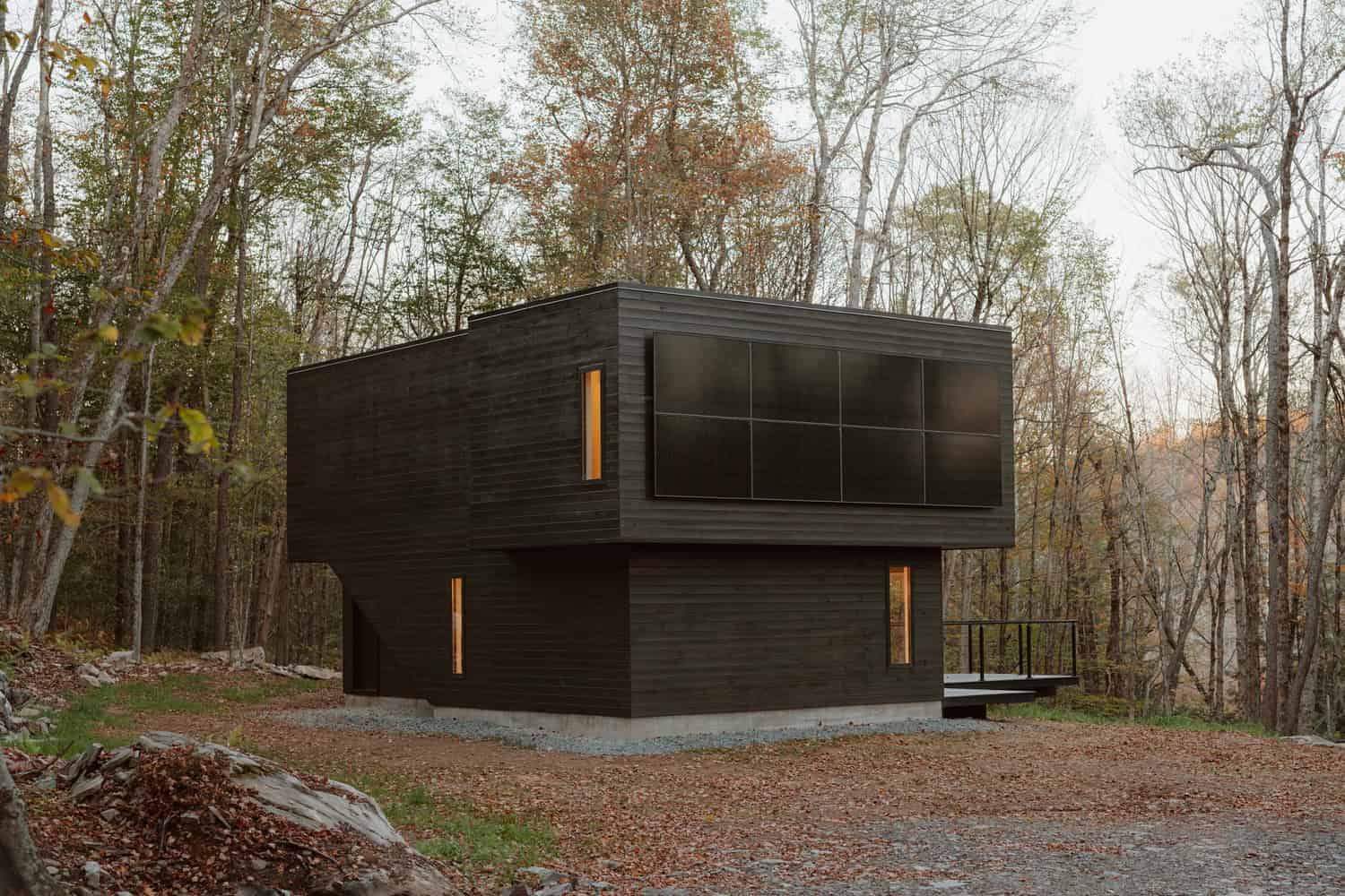 Contemporary black modern house in a forest setting with sleek design and large windows, showcasing innovative architecture and eco-friendly materials in a wooded environment.