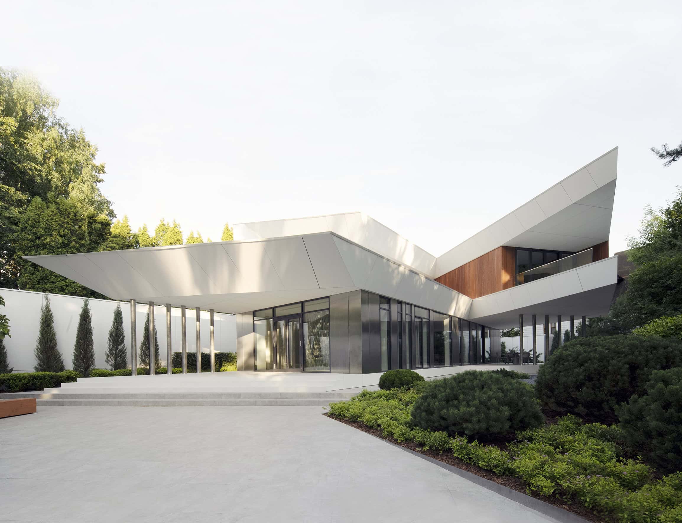 Sleek modern architectural house with sharp geometric design, large glass windows, and minimalist landscaping, showcasing contemporary luxury home architecture and innovative design elements.