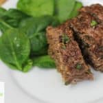 Low carb meatloaf beef and onion with chopped spinach on a white plate