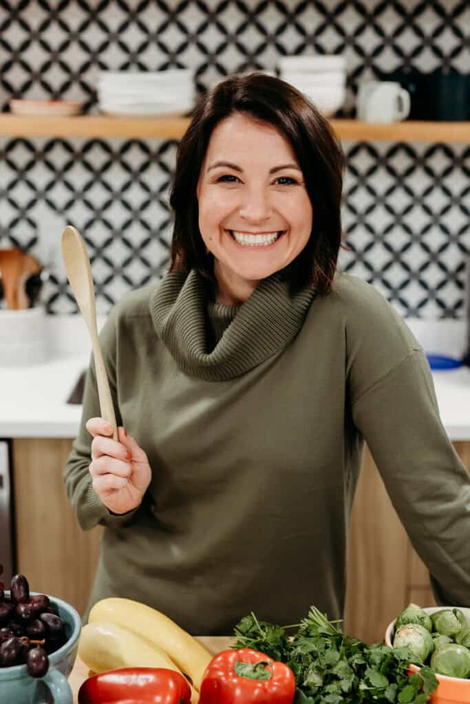 Steph Wagner MS RDN bariatric dietitian in the kitchen holding a wooden spoon