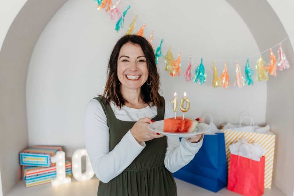 steph wagner holding plate of watermelon with 10 candles and birthday banner behind