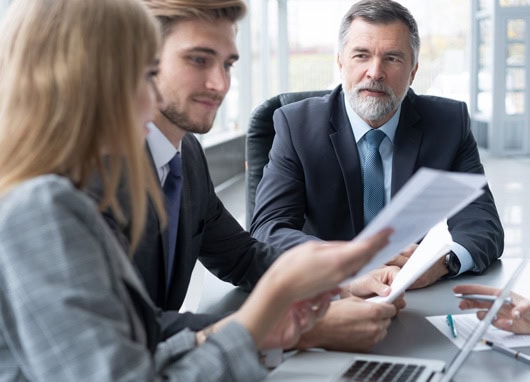 stock image two men and woman having discussion over paperwork