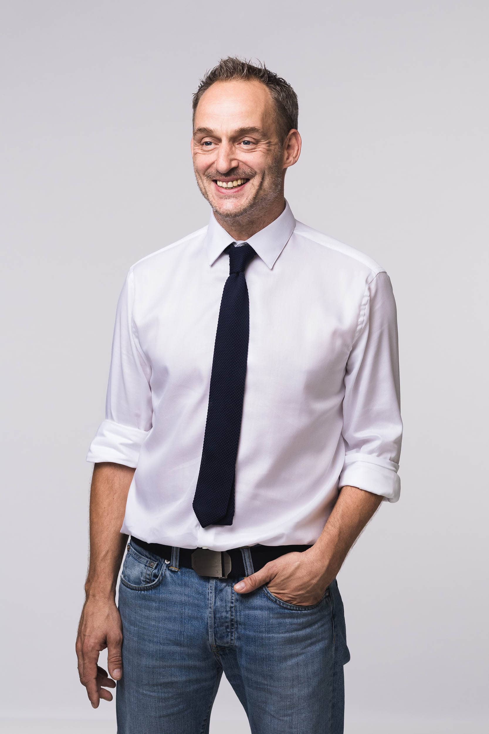 portrait of smiling man wearing white shirt black tie and jeans