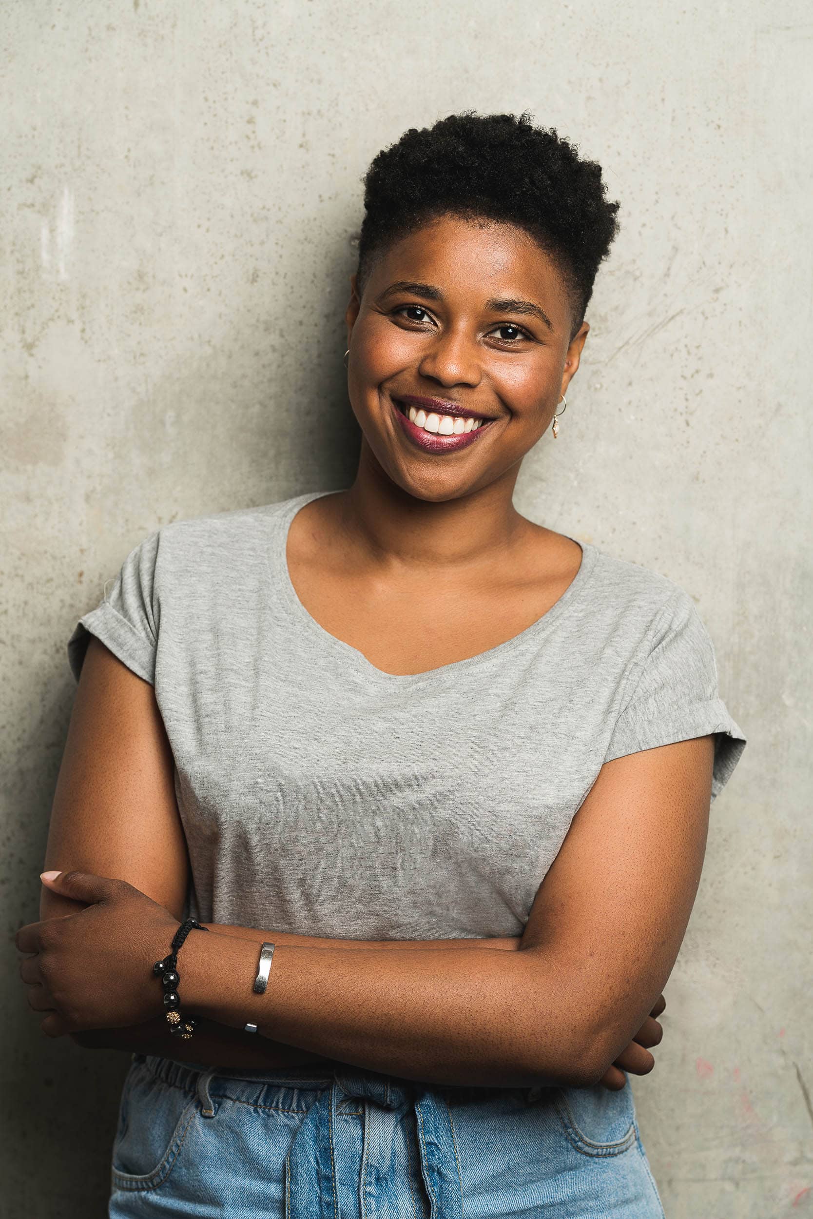 young female smiling leaning against concrete wall
