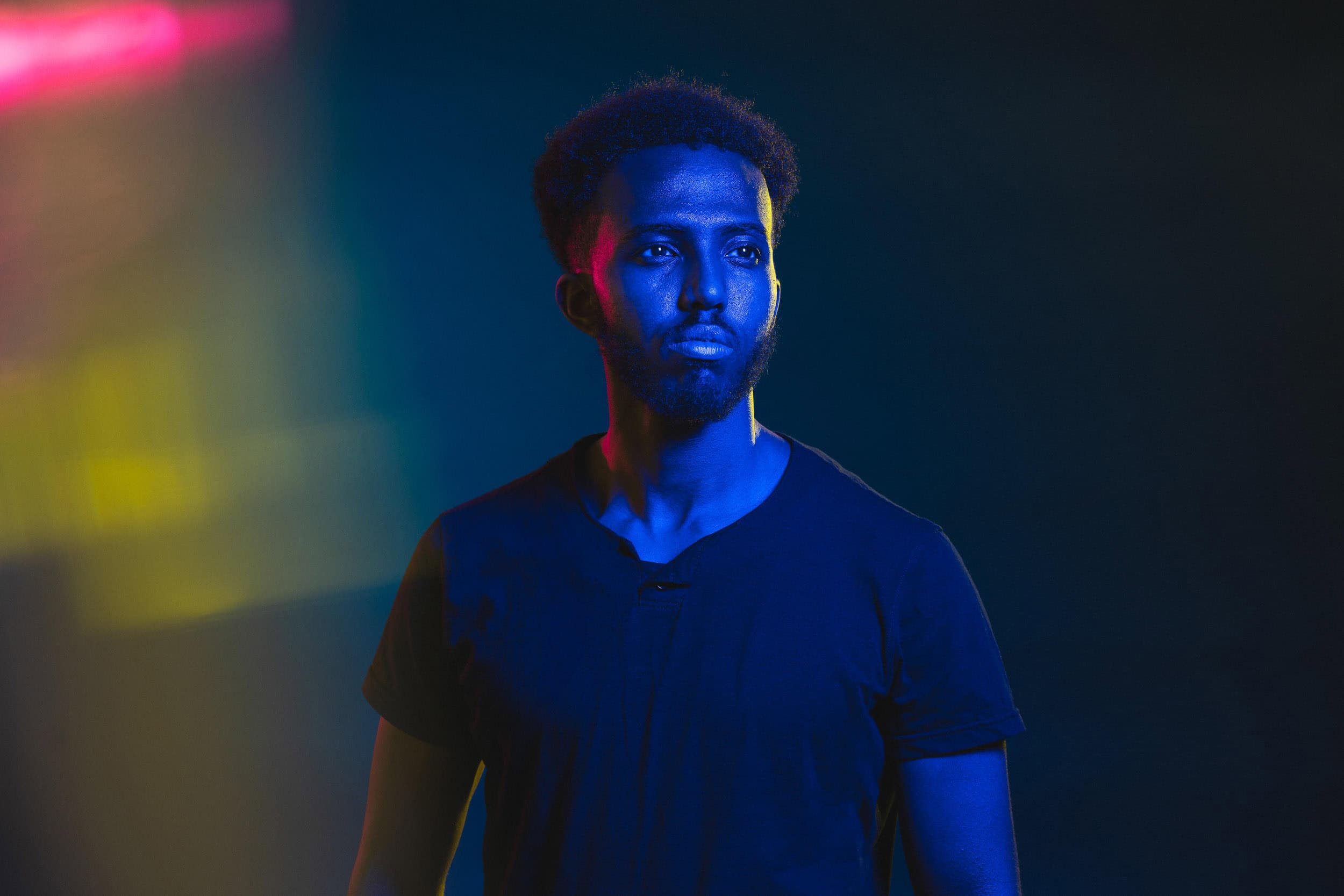studio-portrait-of-young-male-with-blue-yellow-and-magenta-lighting
