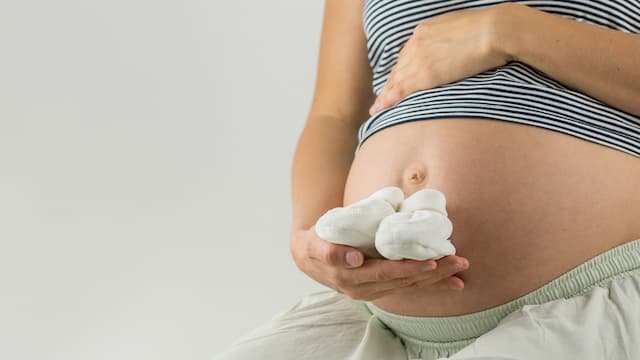 A pregnant woman holding booties