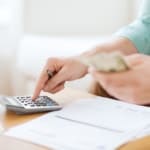 Person using calculator and handling financial documents for bankruptcy filing.