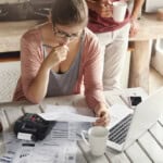 A Greensboro, NC citizen sits at her table reviewing her owed debt and researching debt settlement attorneys in Greensboro, NC.