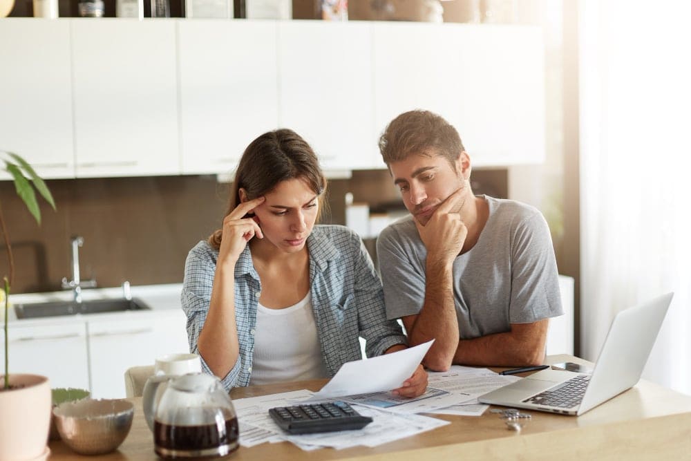 A couple sitting at their table looks over the debt that they're in as they consider a debt settlement attorney.