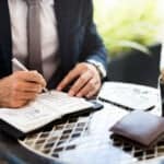 A Greensboro, NC tax attorney sits at this desk, writing notes for a client.